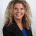 a woman with curly blond hair wearing a black jacket