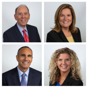 Four smiling people wearing business attire