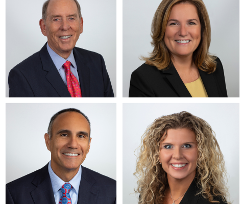 Four smiling people wearing business attire