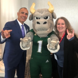 Man and woman posing with bull mascot