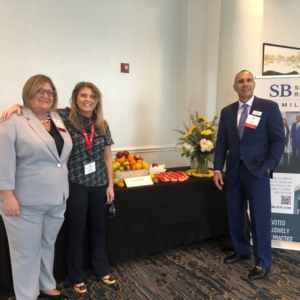 Two women and a man in business attire at an exhibit table