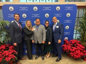 a group of people posing in front of a blue backdrop with red plants on the floor