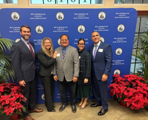a group of people posing in front of a blue backdrop with red plants on the floor
