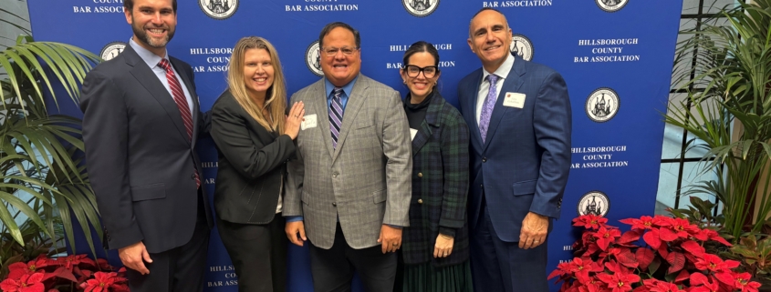 a group of people posing in front of a blue backdrop with red plants on the floor